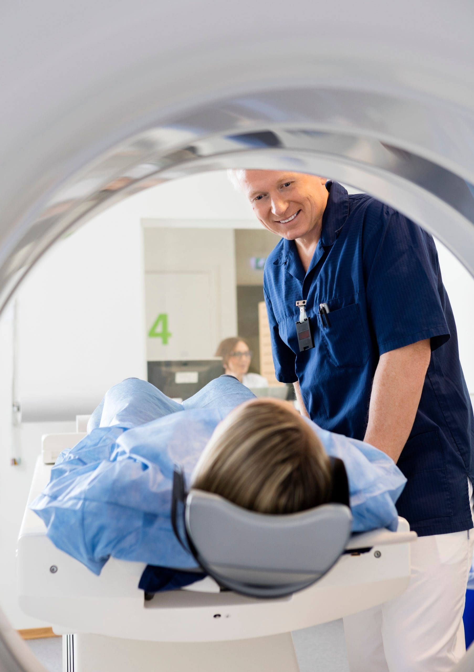 Medical Professional Looking At Female Patient Undergoing CT Sca