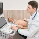 Physician scanning heart of male in the hospital